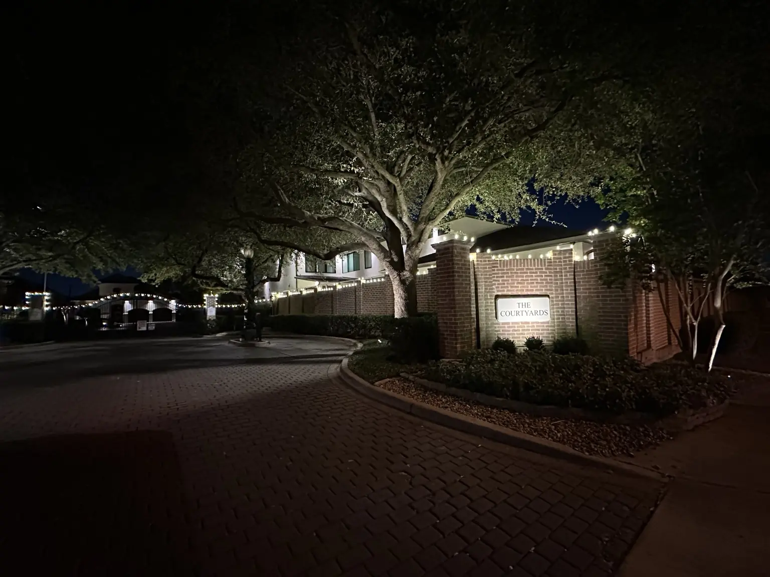 HOA community entrance walls, columns and gates outlined with warm-white Christmas lights