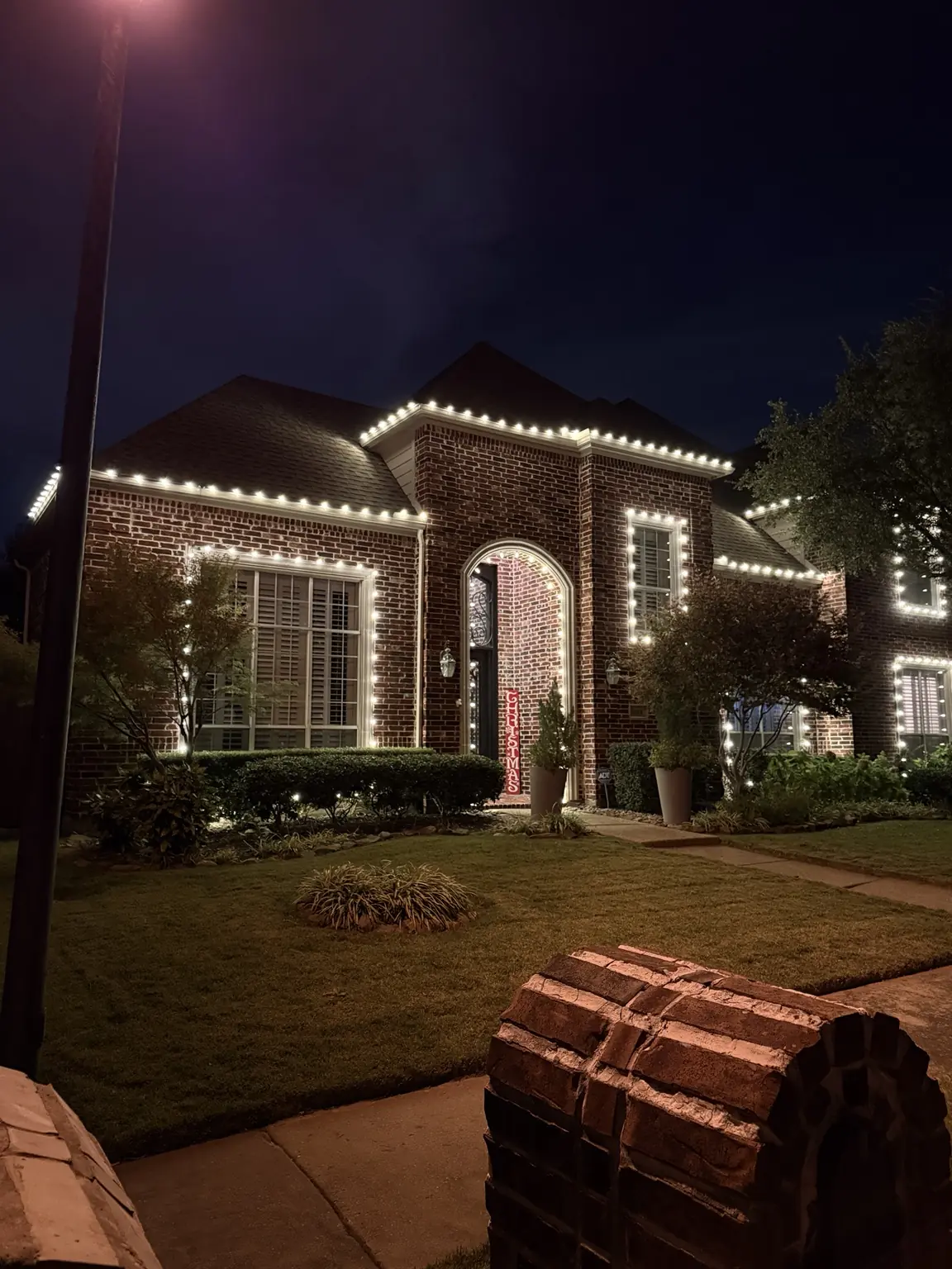 Warm-White Roofline Lights on Brick Home | Elf's Christmas Lights Brick home outlined with professionally spaced warm-white roofline and window Christmas lights