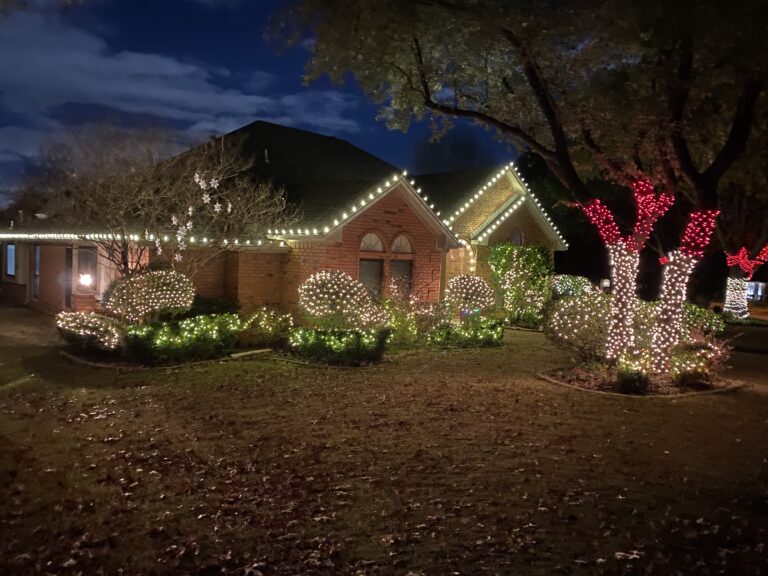Elegant countryside home in Country Ridge & Twin Lakes Murphy, Texas decorated with glowing holiday lights.